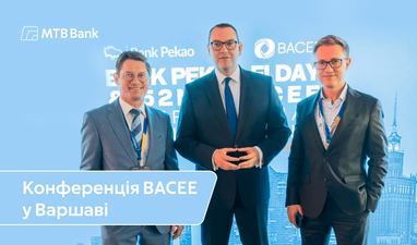 Три представники банку MTB на конференції BACEE у Варшаві стоять перед бренд-волом.