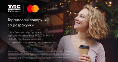 Усміхнена молода жінка з тримає стакан кави та здійснює безготівкову оплату через платіжний термінал