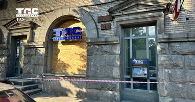 Будівля відділення Таскомбанку після пошкодження. Вікна забиті дерев’яними плитами, а вздовж кам’яного фасаду натягнуто червоно-білу обмежувальну стрічку