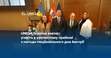 Представители Uniqa Украина на торжественном приеме по случаю Национального дня Австрии. Четыре человека позируют для фото на фоне флагов Украины, Австрии и ЕС.