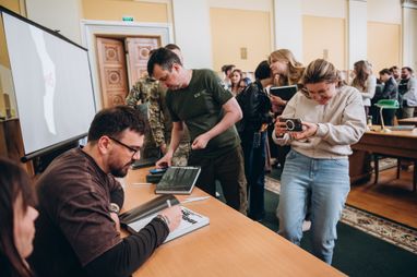 На зображенні зафіксовано момент автограф-сесії та презентації книги Костянтина та Влади Ліберових «Очі війни».