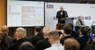 Спікер виступає за трибуною перед аудиторією. На задньому плані розміщено логотип банку