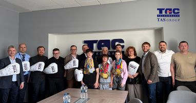 Групове фото в офіційному приміщенні Таскомбанку. У центрі стоять діти з великою кількістю нагородних медалей на шиї. Біля них розмістилися дорослі, кілька з яких тримають великі білі боксерські рукавички з корпоративними логотипами та автографами