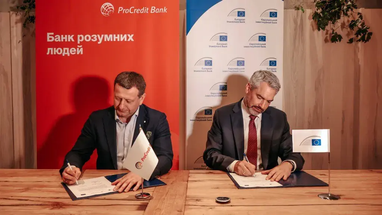 Подписание официального соглашения за столом на фоне брендированных баннеров