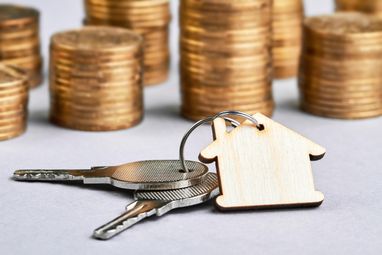 Брелок з ключами від квартири на тлі стопки монет