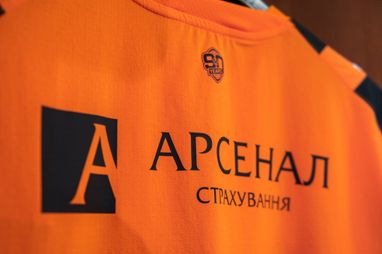 Крупный план оранжевой футболки с логотипом «Арсенал Страхование».