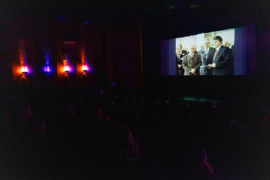 Просмотр кинозала: Зрители в темном зале наблюдают за кадрами на экране во время показа