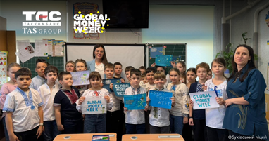 Фотографія школярів обухівського ліцею у вишиванках у навчальному класі. Вони разом із двома жінками стоять біля парт і тримають власні малюнки