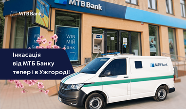 Белый инкассаторский фургон МТБ Банка припаркован возле отделения банка, слева надпись «Инкассация от МТБ Банка теперь и в Ужгороде!», а также логотип МТБ Банк